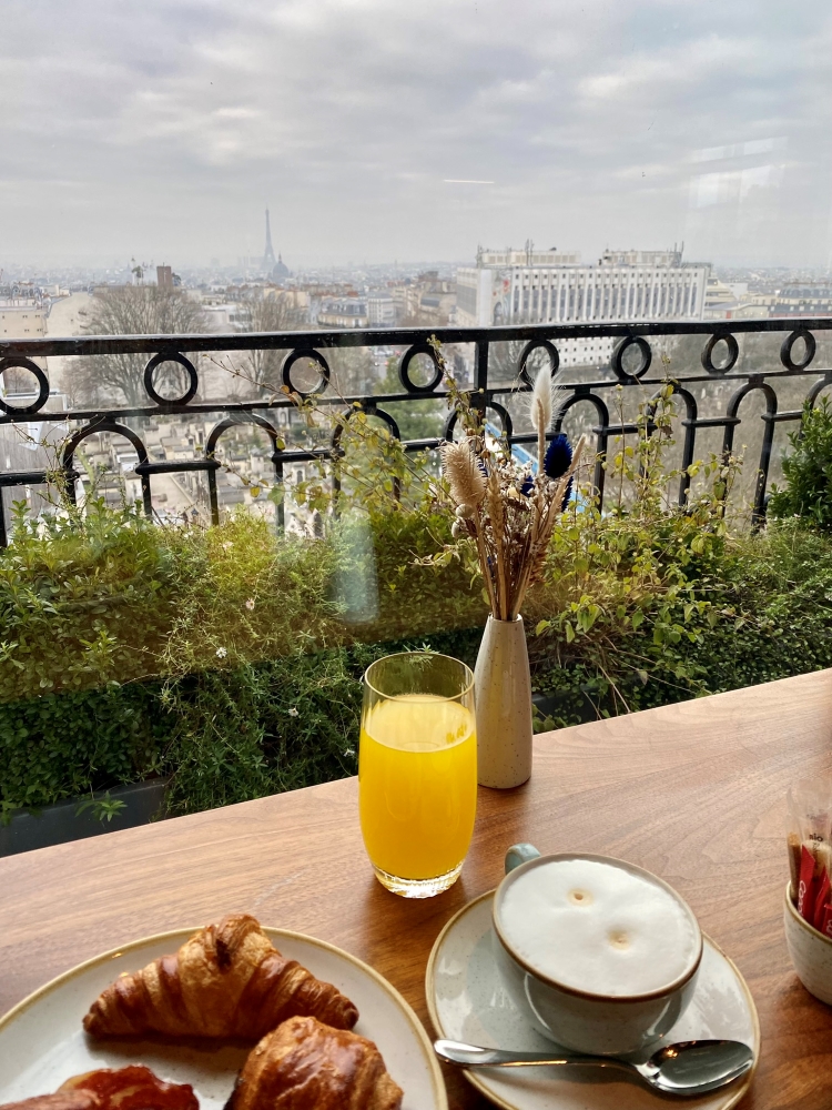 orange juice, coffee and pastries on a table with a view over Paris towards the Eiffel Tower