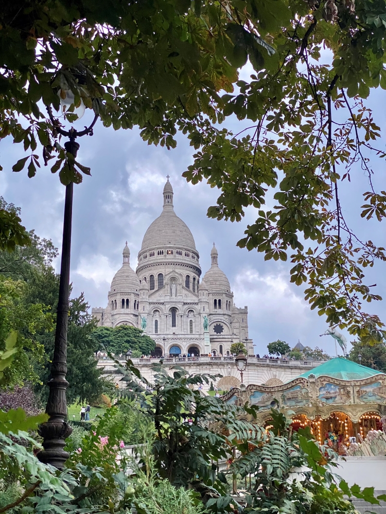 white domes cathedral seen through trees with a fairground in front of it