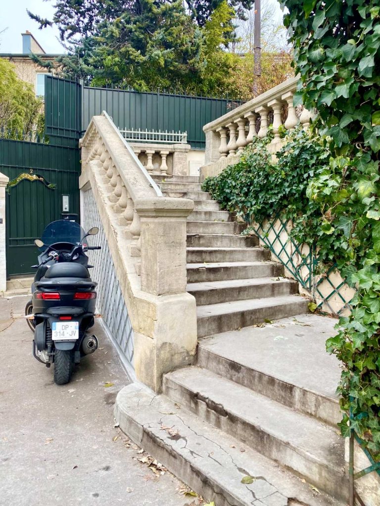 cream coloured stone steps with ivy on them and a motorbike parked next to them