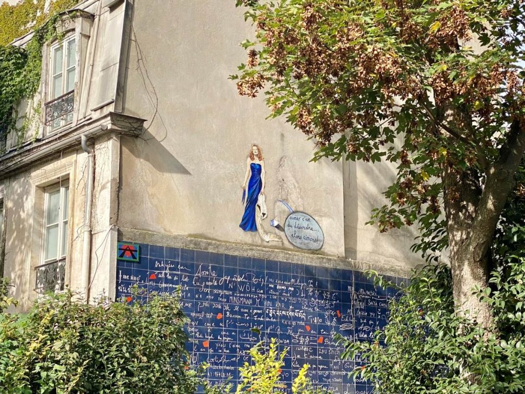 wall of a house decorated with blue tiles with white writing on them and a drawing of a woman in a blue evening gown